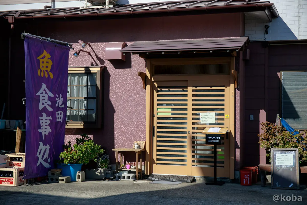 大きな垂れ幕が目を引く外観入口、店頭右側に記名台