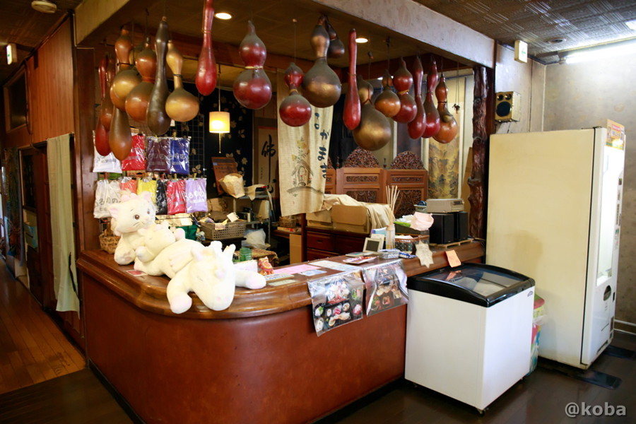 ホール左奥にある受付場所、上部から 大きなひょうたんが幾つも ぶら下がっています、ひょうたんは 囲炉裏の影響か煤がかぶっている。