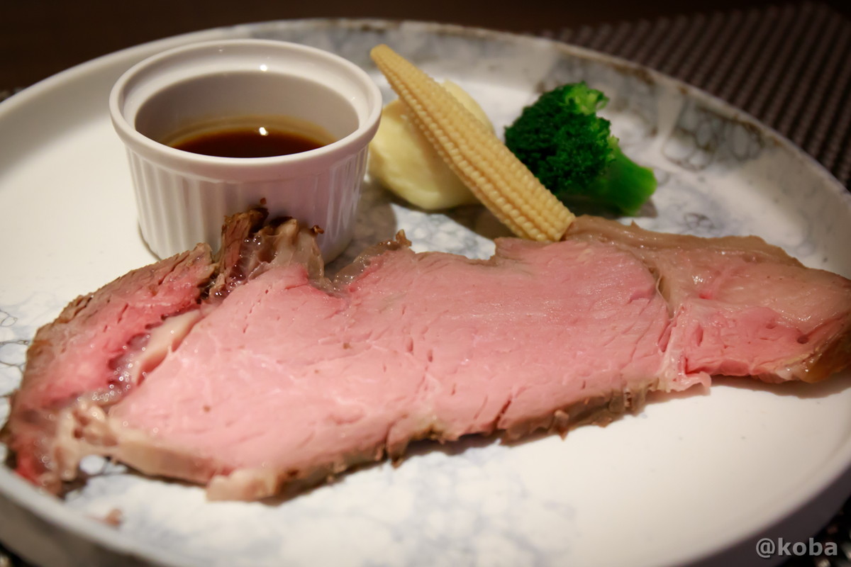 ホテルハーヴェスト勝浦の夕食メイン。特製グレイビーソースがたっぷりかかったローストビーフに、ポテト、ヤングコーン、ブロッコリーが添えられた写真。