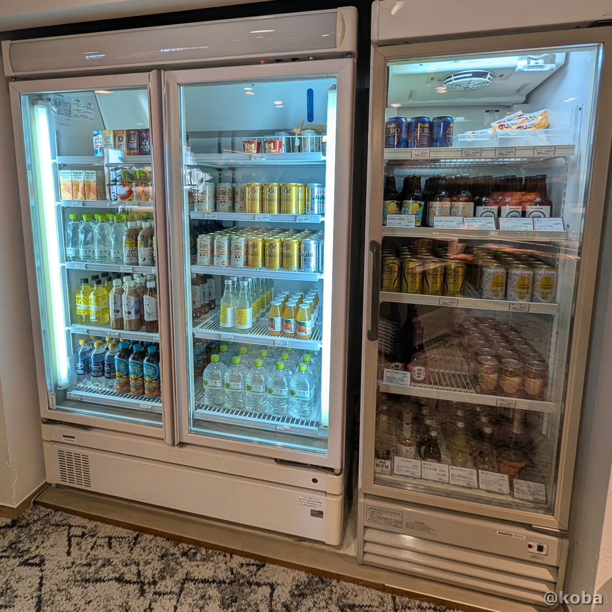 ホテルハーヴェスト勝浦の売店にある冷蔵庫。ソフトドリンクや缶ビール、クラフト瓶ビール、ハイボール、日本酒など、種類豊富なお酒と飲料が並んでいる写真。