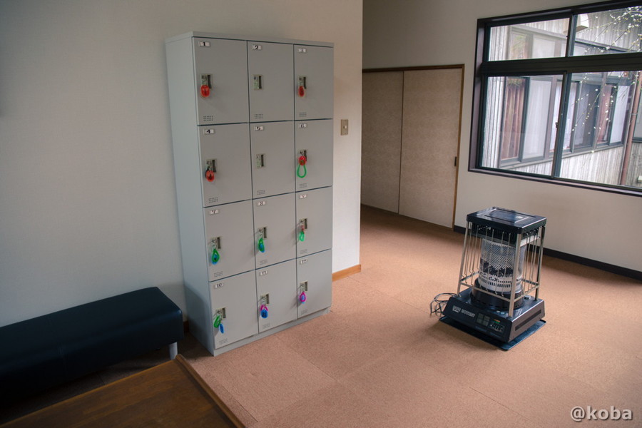 小糸川温泉の館内。ホール横に設置された荷物用のロッカーと、暖を取るためのストーブの写真。