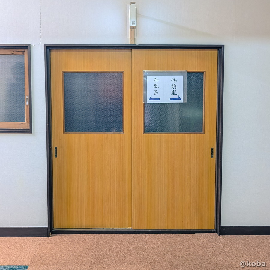 小糸川温泉の館内廊下に掲示された、「←お風呂」「休憩室→」と書かれた案内表示の写真。