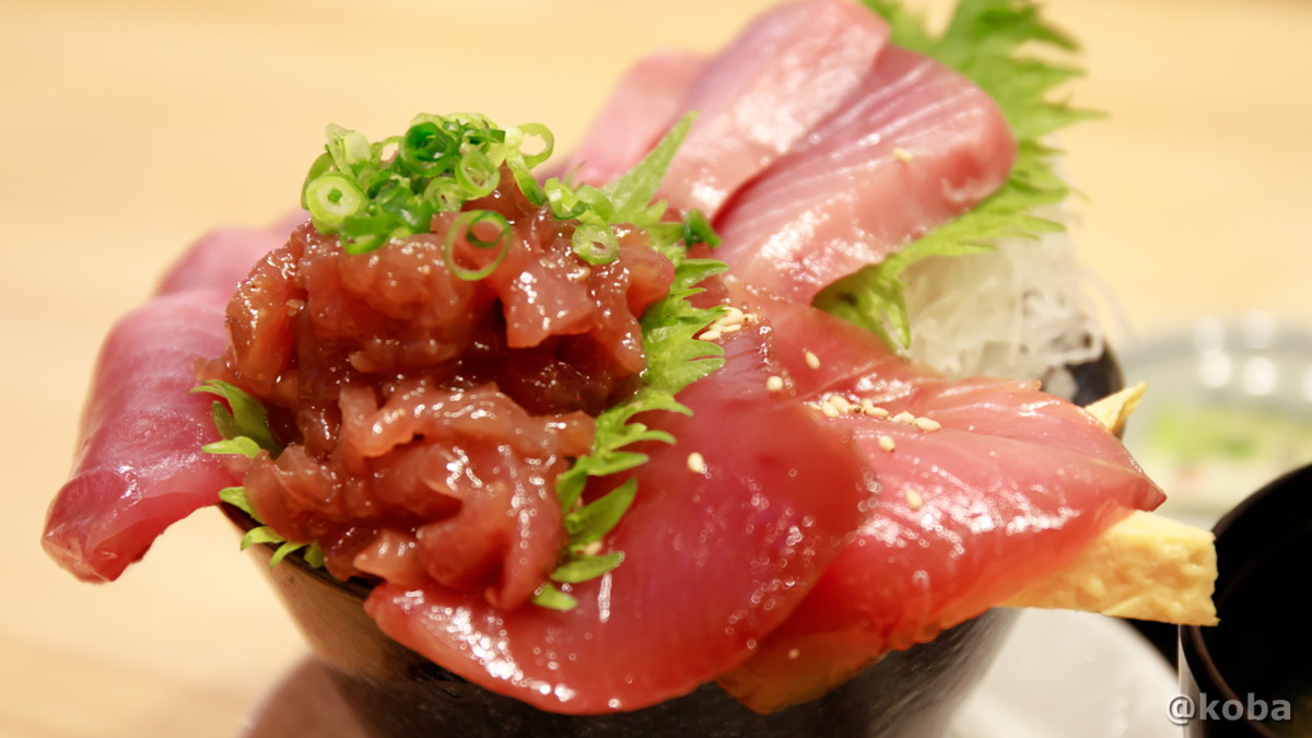 鮮やかなメジマグロの赤身の上に、たたきが盛り付けられた立体感のある、「メジマグロ丼」の寄りの写真。