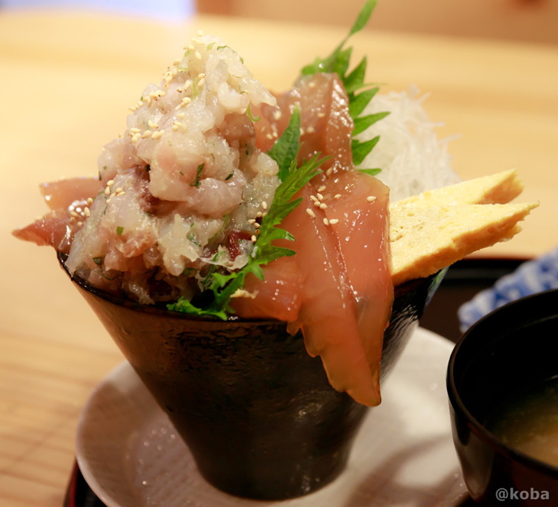 マルニ水産の「よくばりづけ丼」のクローズアップ写真。円錐を逆さまにしたようなシャープな器に、具材が立体的に盛り付けられている。