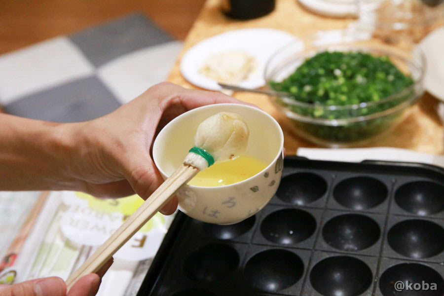 割り箸の先に丸めたクッキングペーパーを輪ゴムで留め、自作した油引きを油に浸している様子