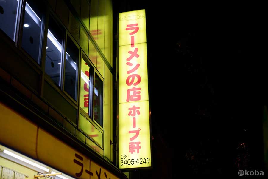 暗闇に浮かび上がる「ラーメンの店 ホープ軒」の特徴的な黄色い看板