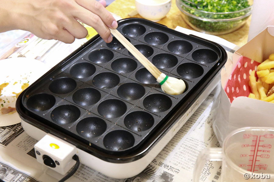 自作の油引きを使って、たこ焼き器の穴に油をたっぷりと塗っている様子