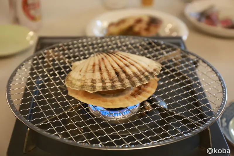 トングなどを使い手際よく上の平らな貝殻を外している作業の様子