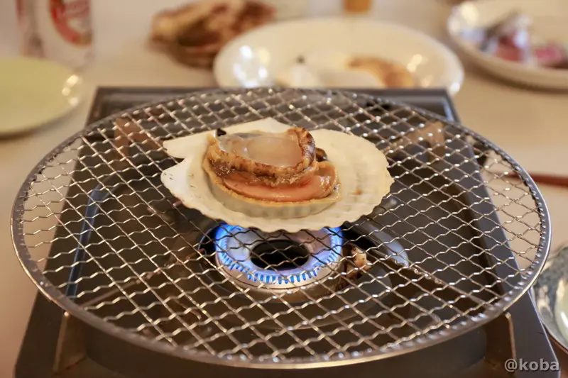 丸い貝殻を下にして網に戻しグツグツと沸騰しながら焼けるホタテの身