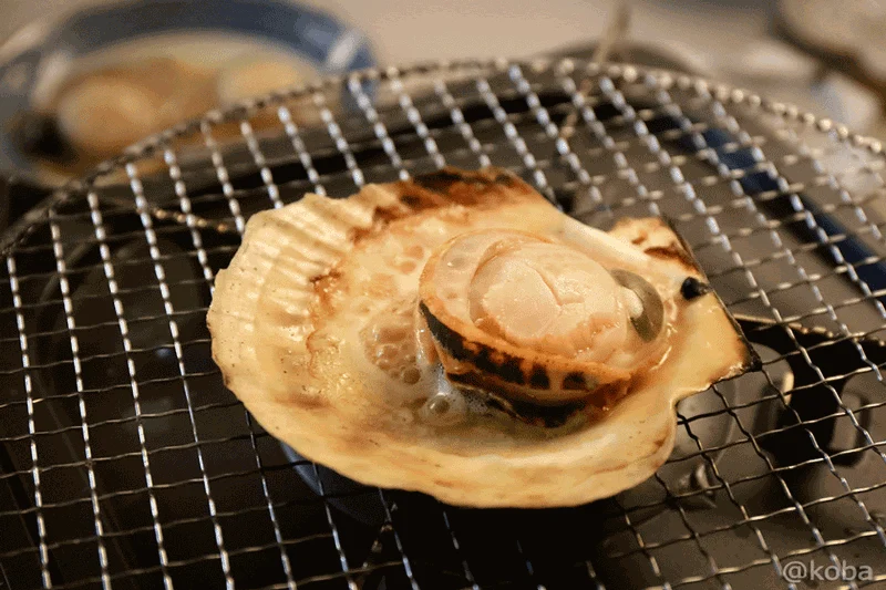 丸い貝殻を器にして旨味たっぷりの汁と一緒に焼き上がった完成品のホタテ